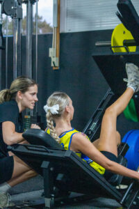 Young athlete with patellofemoral pain doing knee pain treatment exercises under supervision